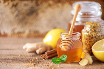 Wall Mural - Alternative medicine concept. Ingredients for flu fighting natural hot drink. Copy space. Lemon, ginger, mint, honey, apple and spices on wooden background