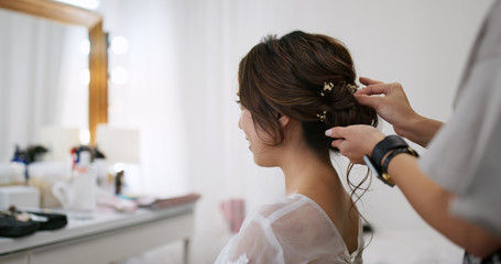 Hairdresser creating a hairstyle for bride in salon