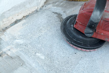 Construction Worker Uses A Concrete Grinder For Removing Tile Glue And Resin During Renovation Work