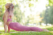 © AnnaStills - Beautiful healhy woman in pink clothing stretching on the exercise mat during her sports training outdoors in the park