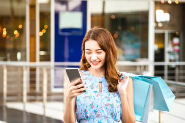 Wall Mural - Young asian shopper woman use smartphone with shopping bags