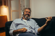 © cherryandbees - handsome middle aged man listening music wearing headset, sitting sofa at his home