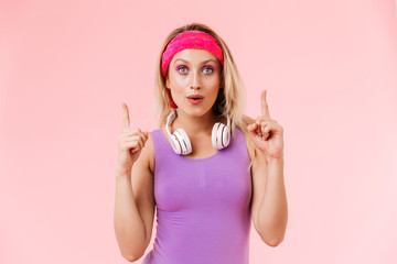 Poster - Image of nice surprised woman pointing fingers upward with headphones