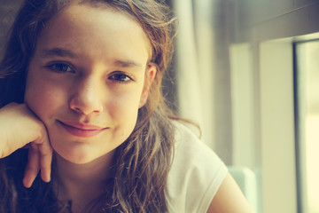 Teenage girl is sitting indoor in urban cafe. Casual portrait of teenager girl. Toned.