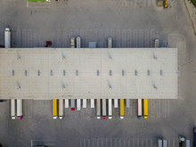 Aerial View Of Goods Warehouse. Logistics Center In Industrial City Zone From Above. Aerial View Of Trucks Loading At Logistic Center. View From Drone.