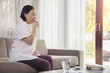 © anon - old age, health problem, vision and people concept - close up of Asian senior woman  sitting on sofa and having headache at home.She may had Headache Symptoms.She looks pain  and sick
