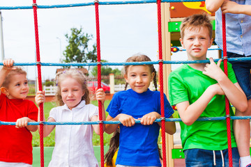 Wall Mural - Friends on climbing net looking at camera