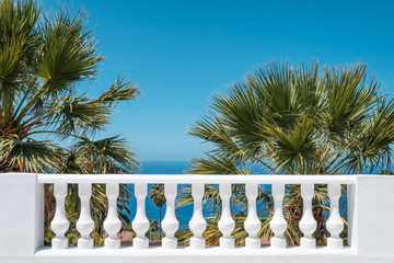 Wall Mural - terrace balluster with ocean view, blue sky and palm tree background