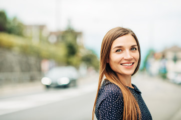 Outdoor portrait of attractive young woman with long brown hair