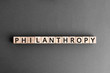 Philanthropy - word from wooden blocks with letters, to help poor people altruism charity philanthropy concept,  top view on grey background