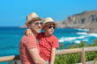 © Artem - Dad and son in sun hats and sunglasses and similar clothes standing on cliff against wonderful sea view. They smiling and enjoying their summer vacations.