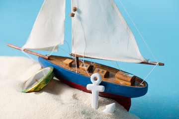 Sticker - miniature ship near compass and anchor in white sand isolated on blue