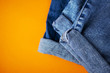 © Ольга Холявина - Blue jeans tucked up. Close-up, orange background, place for text, flat lay top view.
