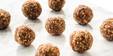 Energy protein balls with healthy ingredients on marble table. Home made with dates, peanut butter, flax and chia seeds, oats, almond and chocolate drops. Food modern pattern on marble table