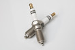 © Дмитрий Ногаев - Two car spark plugs lie on a white table