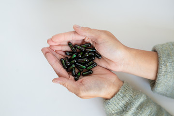 Vitamin Supplements in Green Jar Poured in Hand