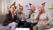 © motortion - Cheerful aged people birthday hats blowing party horns, holiday celebration, fun