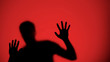 © motortion - Injured male silhouette behind glass, red lights background, warfare concept