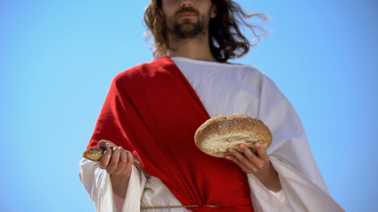 Man in robe holding fish and bread, charity concept to feed hungry, generosity