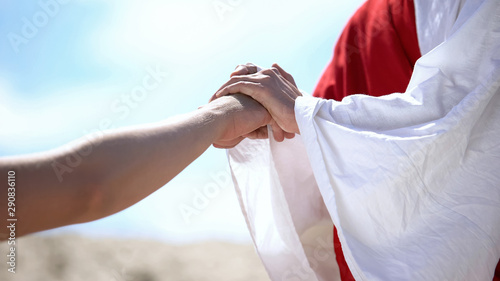 Cuadros en Lienzo Jesus holding male hand to bless and heal Christian, religious miracle, closeup