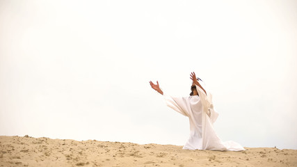 Bedouin raising palms to sky, asking Allah for help and mercy, praying on knees