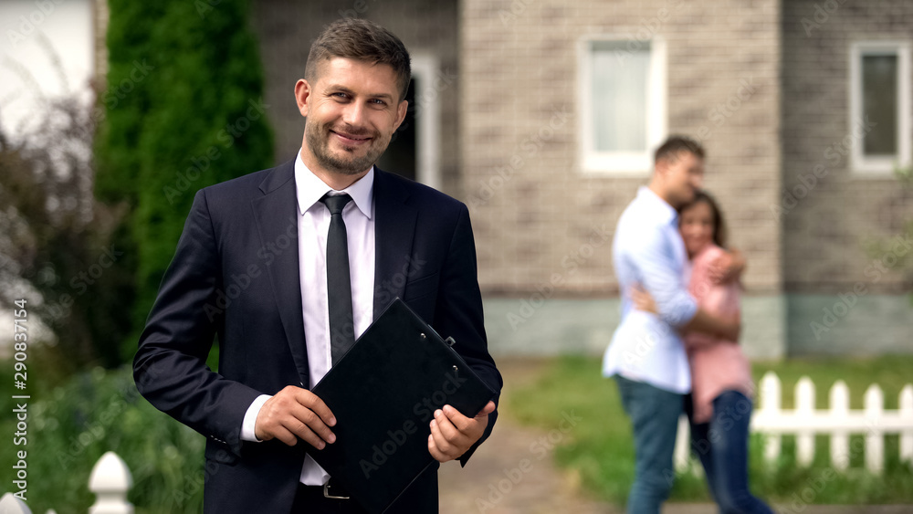 Smiling broker standing with documents, happy family hugging near their new home - obrazy, fototapety, plakaty 