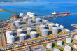 © aapsky - Aerial view of large fuel storage tanks at oil refinery industrial zone in the cargo seaport, and ship tanker at unloading.