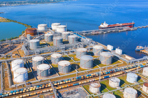 Cuadros en Lienzo Aerial view of large fuel storage tanks at oil refinery industrial zone in the cargo seaport, and ship tanker at unloading