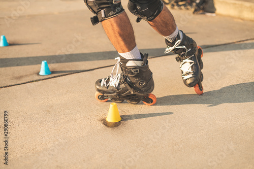 Fotografía Close-up view of the rollers of a caucasian man, doing rollerblading, inline skating, performing on a slalom course on asphalt surface