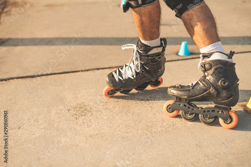 Fotomural Close-up view of the rollers of a caucasian man, doing rollerblading, inline skating, performing on a slalom course on asphalt surface