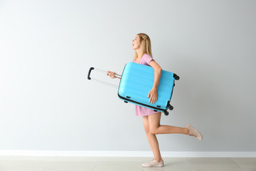 Poster - Running beautiful woman with luggage near light wall