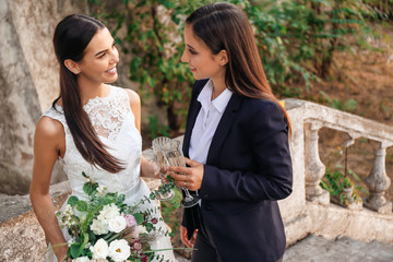 Poster - Beautiful lesbian couple with glasses of champagne on their wedding day outdoors