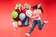 © Вячеслав Косько - Laughing woman friend having fun jumping and smiling with colorful air balloon isolated at red studio background. Happy female teenager celebrating enjoying party posing together full shot