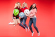© Вячеслав Косько - Laughing woman friend having fun jumping and smiling with colorful air balloon isolated at red studio background. Happy female teenager celebrating enjoying party posing together full shot