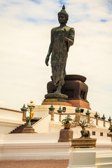 Standing buddha for worship in Phutthamonthon Park with sunset sky and reflective light,beautiful background