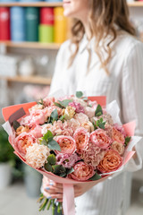 Wall Mural - beautiful fresh cut bouquet of mixed flowers in woman hand. the work of the florist at a flower shop. Delicate Pastel tones color