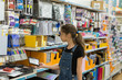The girl is choosing school supplies at a store. Buying school tools in a English shop.