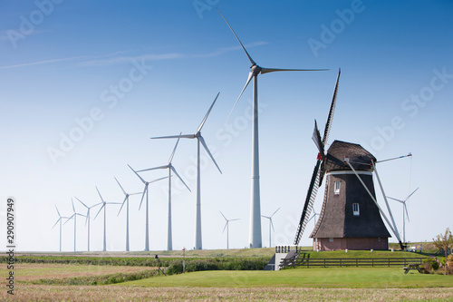 Fotografía old dutch windmill and modern wind turbines against blue sky in dutch province o