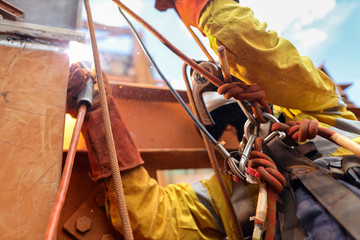 Overhead wide pic of secondary safety back up hard ling device clipping into abseiling harness loop while rope access abseiler performing hot work preventing from falling if rope burn or cut     