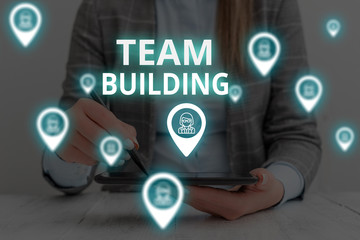 Text sign showing Team Building. Business photo text Types of activities used to enhance social relations Woman wear formal work suit presenting presentation using smart device