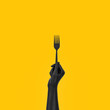 © vpanteon - Black Hand holding fork isolated on yellow, abstract food concept banner.  3d rendering