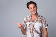 © Ranta Images - Portrait of happy handsome Hispanic tourist man pointing finger to the side