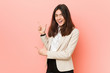 © Asier - Young brunette business woman against a pink background pointing with forefingers to a copy space, expressing excitement and desire.