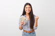 © Asier - Young arab woman holding dollars cheering carefree and excited. Victory concept.