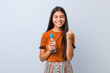 Young arab woman holding a water bottle cheering carefree and excited. Victory concept.