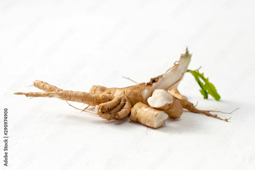 Raw chicory root (Cichorium intybus) with leaves on a white background. - obrazy, fototapety, plakaty 