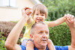 © Tetiana Soares - Cute happy little grandson sitting on his grandfather shoulders neck smiling and looking at camera. Different generation family bonding. Family love and care