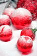 abstract blurred festive winter holiday background. red christmas tree balls in snow. shallow depth. close up. soft selective focus