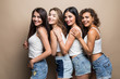 © F8  \ Suport Ukraine - Four attractive women in white shirts and shorts embracing isolated on beige background