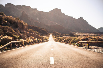 Wall Mural - Beautiful and scenic long way road with focus on foreground - defocused background and travel destination effect with sunilght and mountains